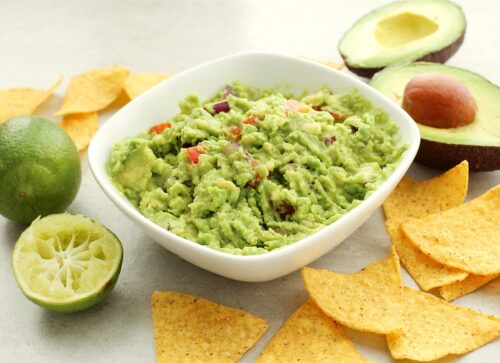 with avocado and chips in the background guacamole sauce