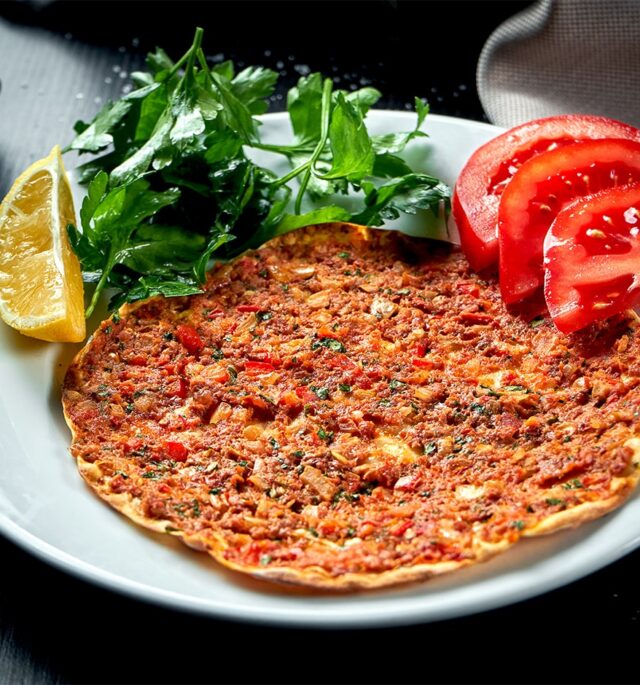 lahmacun served with greens and tomatoes on a plate