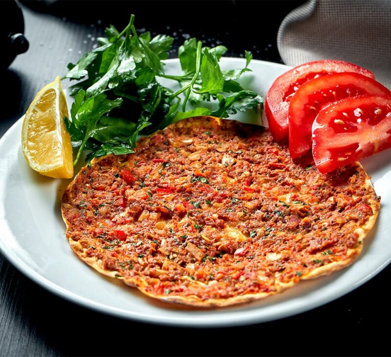 lahmacun served with greens and tomatoes on a plate