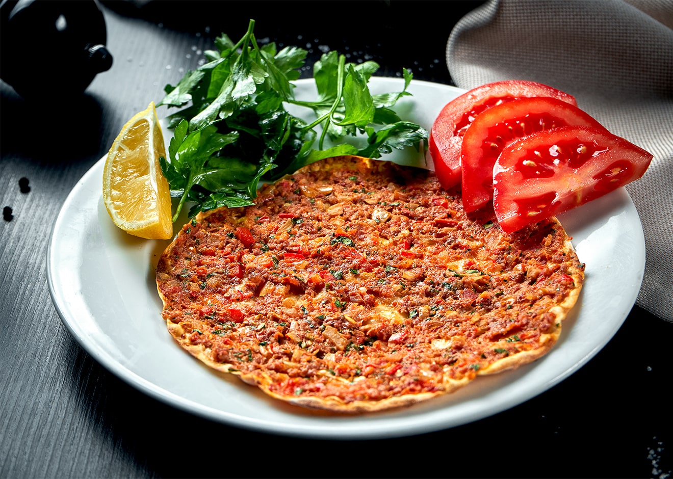 lahmacun served with greens and tomatoes on a plate