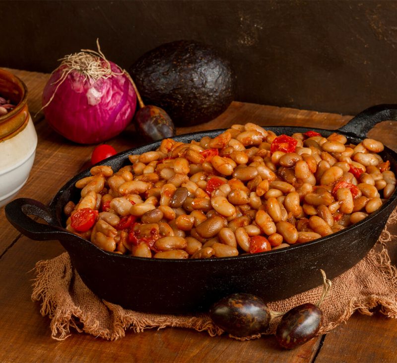 Kuru Fasulye (White Bean Stew) in a metal pan with onion on the table